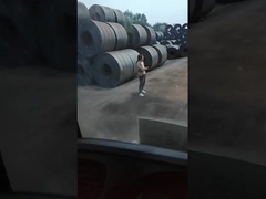 Les bras mécaniques battent les bobines d'acier au carbone